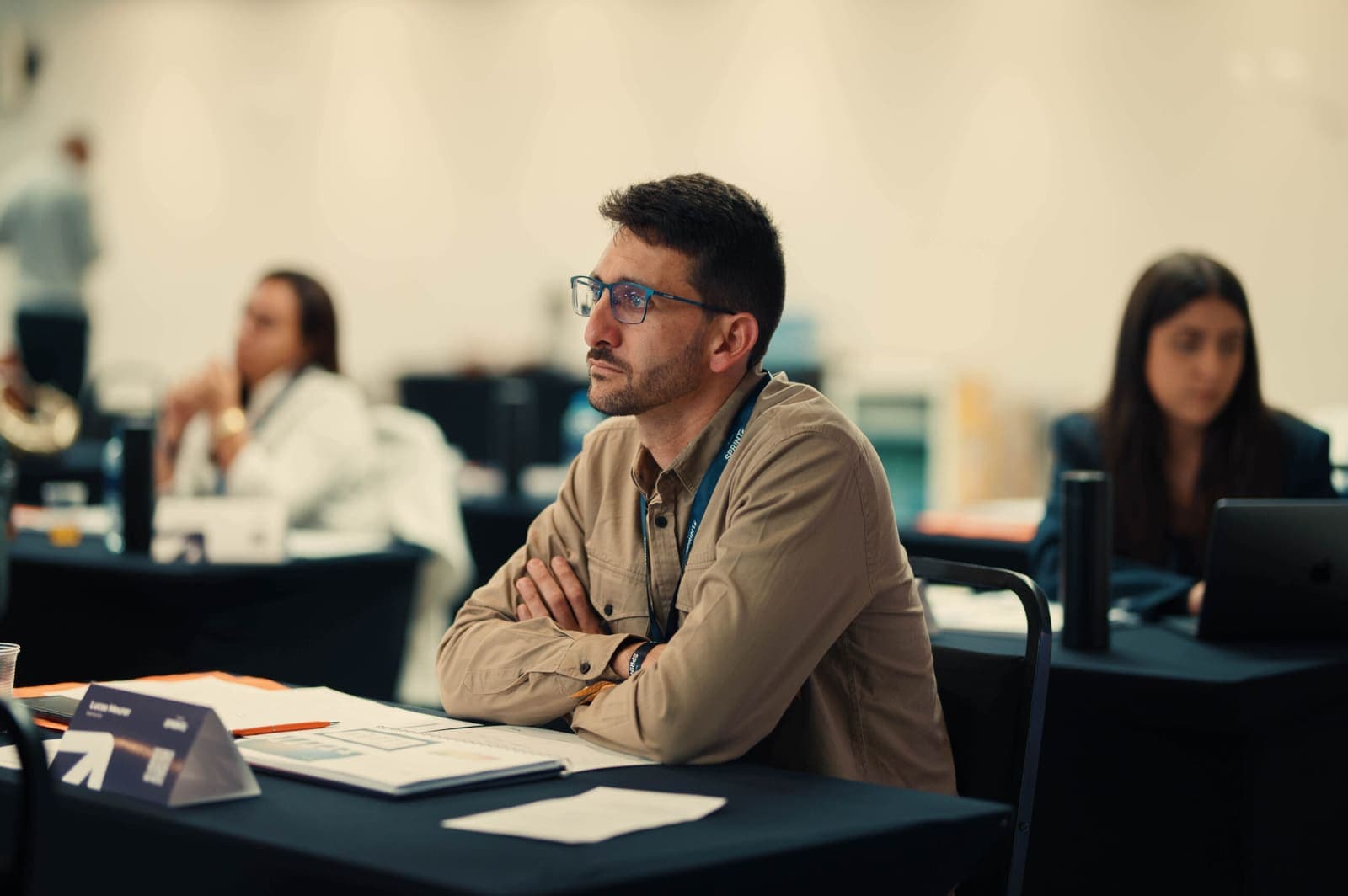 Participante atento à aula, de braços cruzados